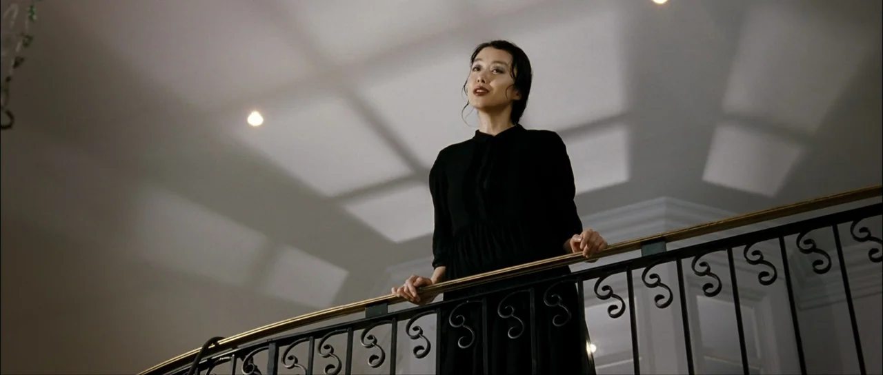 The Housemaid (2010) (2010) movie still: medium — A woman stands on a mezzanine platform looking over a decorative metal railing. The high ceiling…