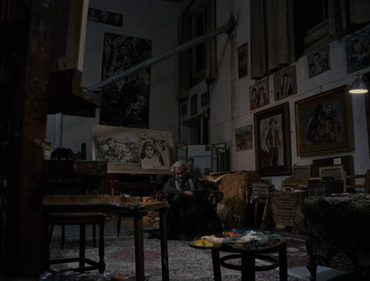 Christ Stopped at Eboli (1979) movie still: wide — A cluttered art studio features walls covered with framed paintings and drawings. An elderly…