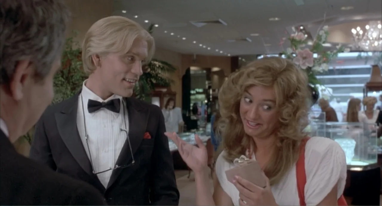 Making Mr. Right (1987) movie still: medium — A well-lit commercial interior with glass display cases showing diamonds and jewelry pieces. A blonde…