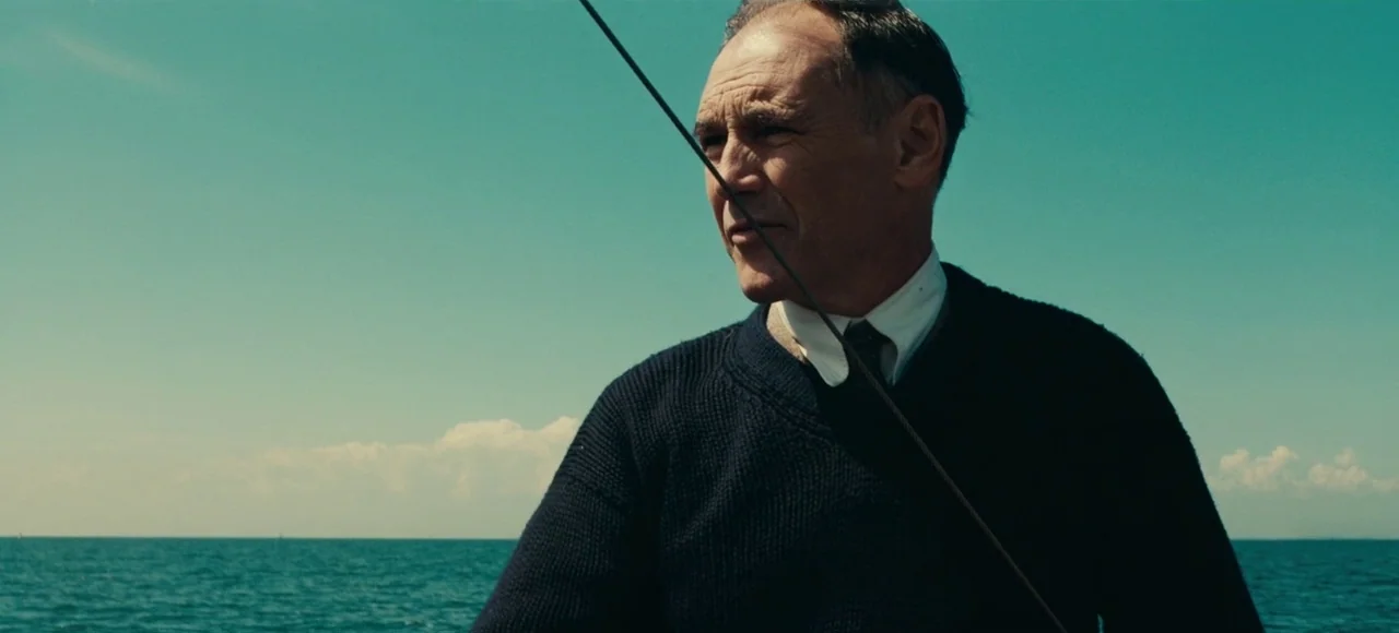 Dunkirk (2017) movie still: medium — An older man stands on a sailboat with an expansive view of the open sea. He gazes into the distance while…