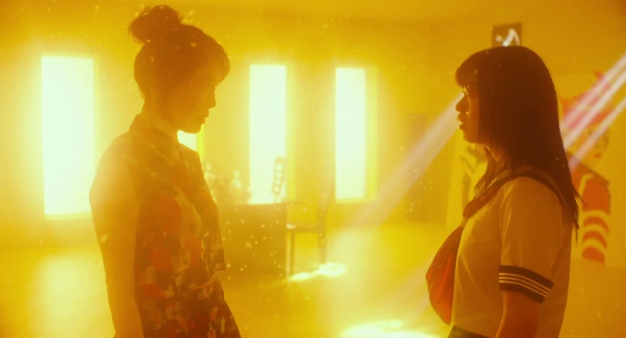 Making of: Antiporno (2016) movie still: medium — An interior space is illuminated by intense yellow light obscuring most background details. Two…