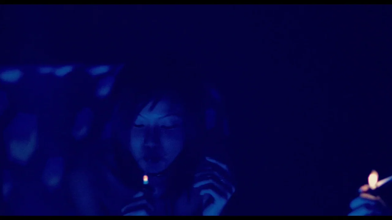 Millennium Mambo (2001) movie still: closeup — A dark, dimly lit environment where a single person holds a flickering flame. The subject is…