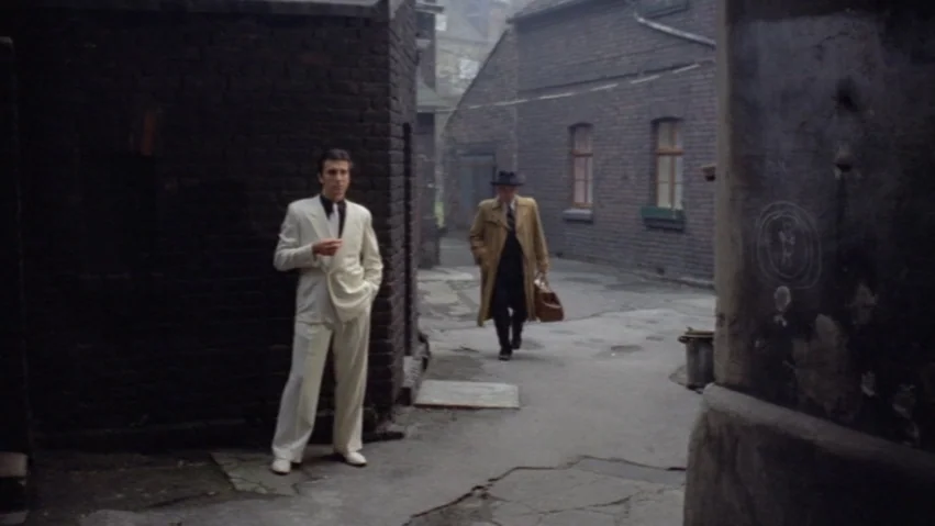 Tenderness of the Wolves (1973) movie still: fullbody — An enclosed urban courtyard surrounded by dark, weathered brick walls and old buildings. A…