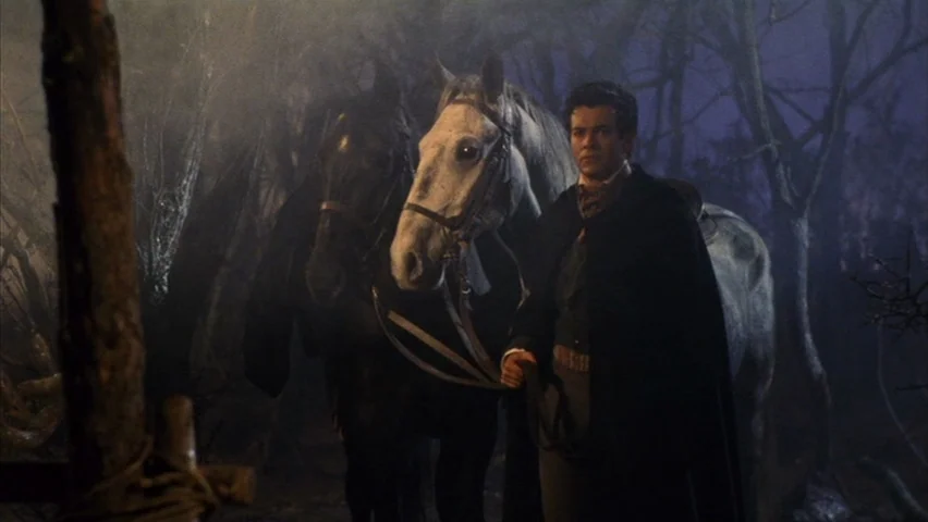 Black Sabbath (1963) movie still: medium — A dense cluster of bare trees stands in a dark and misty night forest. A man in a cloak leads a white and…