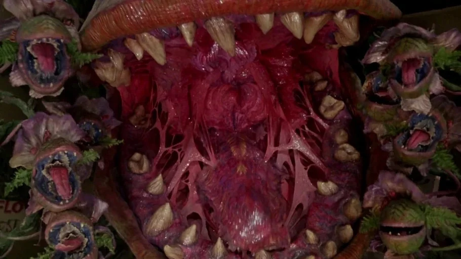 Little Shop of Horrors (1986) movie still: closeup — A gargantuan, toothy carnivorous plant displays its complex and fleshy internal anatomy.…