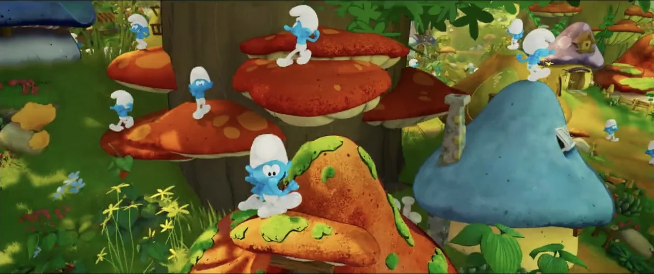 Smurfs (2025) movie still: wide — A fantasy village composed of large mushroom houses nestled in a verdant landscape. Several small blue Smurf…