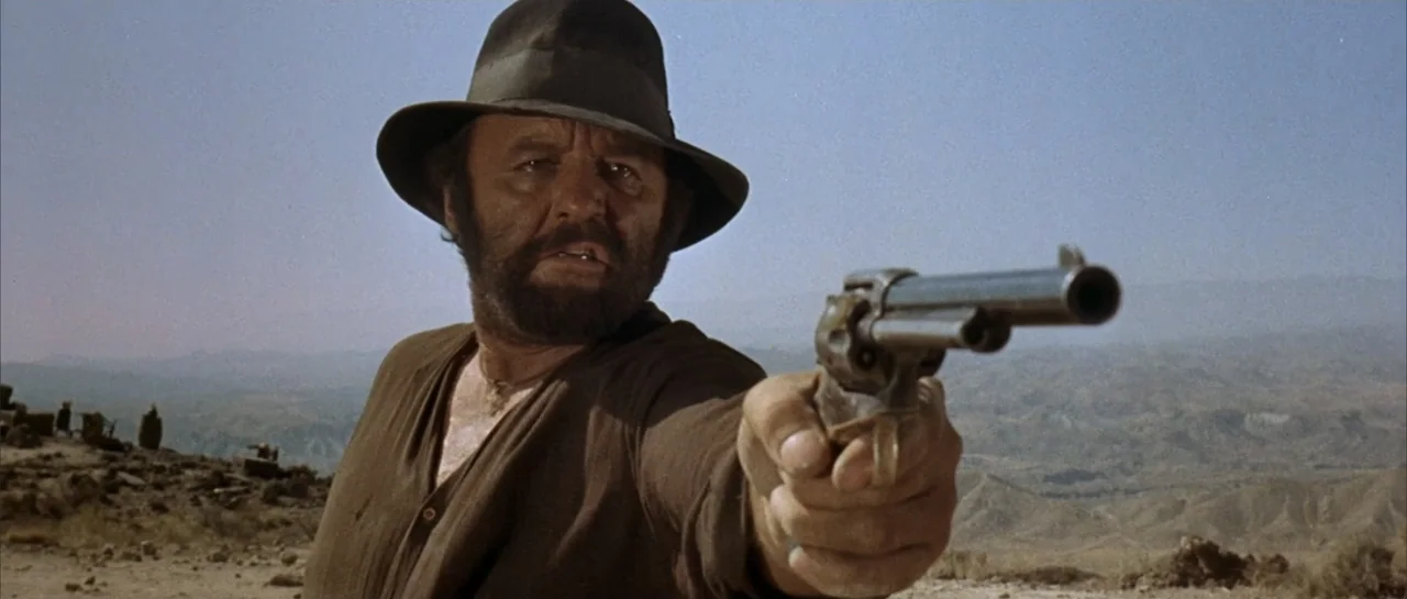 Duck, You Sucker (1971) movie still: medium — An arid, rocky desert landscape stretches into the distance under a clear blue sky. A man in a brown…
