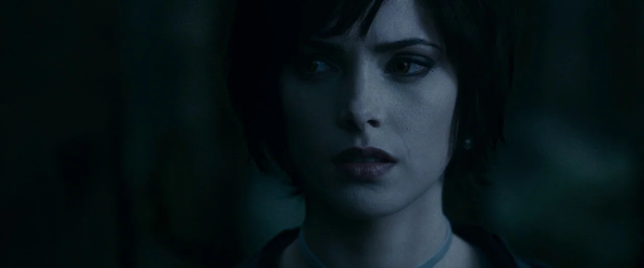 The Twilight Saga: Eclipse (2010) movie still: closeup — A dark, out-of-focus woodland area serves as a backdrop for a close-up shot. A young woman…