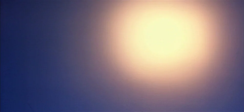 Lawrence Of Arabia movie still: establishing — A featureless abstract background shows a bright circular light source against a blue gradient. The…