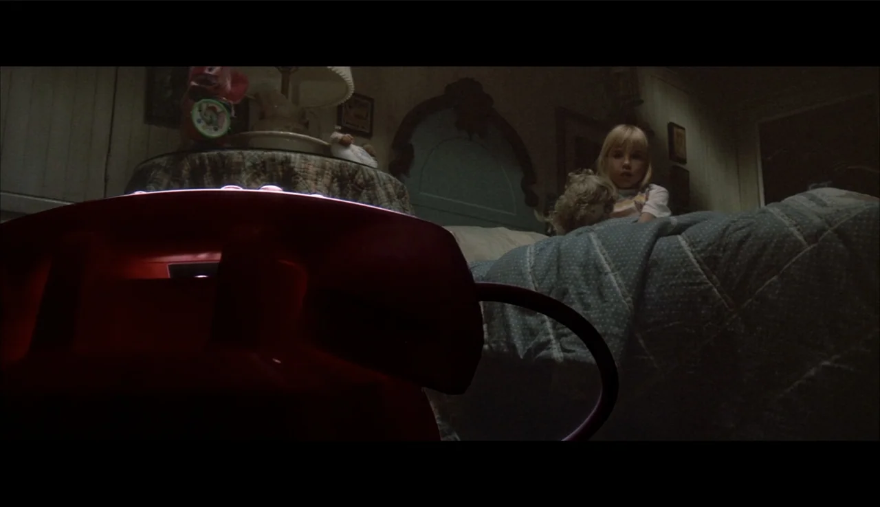 Poltergeist II: The Other Side (1986) movie still: medium — A dimly lit child's room features a bed and a bedside lamp in shadow. A young girl sits…