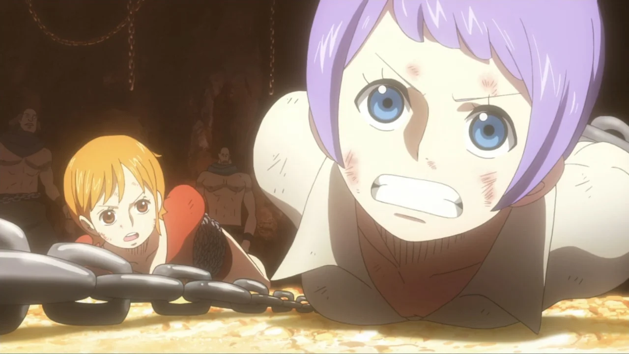 One Piece Film: GOLD (2016) movie still: medium — A dark, rocky dungeon enclosure contains heavy chains strewn across the dusty floor. Two bound…