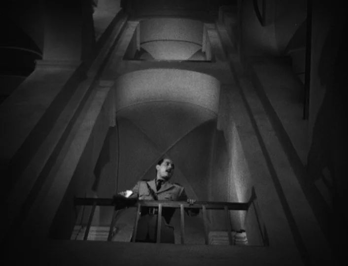 The White Sheik (1952) movie still: wide — A stone balcony overlooks a cavernous room with arched, vaulted ceilings and architectural shadows. A man…