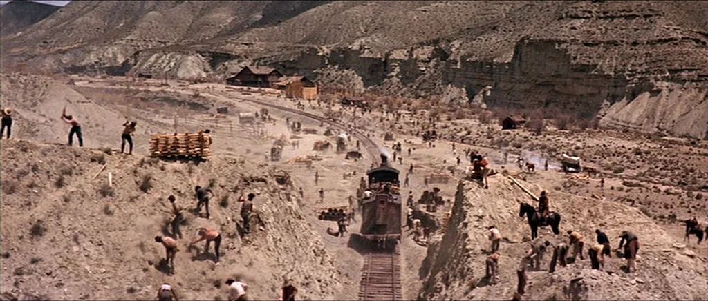 Once Upon A Time In The West (1968) movie still: wide — A vast, arid landscape features numerous laborers digging into rocky hillsides for track…