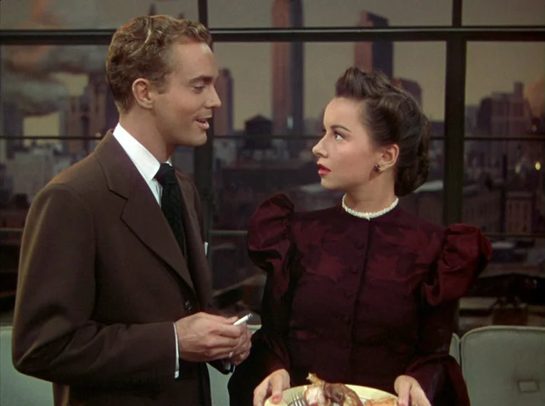 Rope (1948) movie still: medium — A high-rise apartment features a large paneled window overlooking a dark urban skyline. A man and woman in 1940s…
