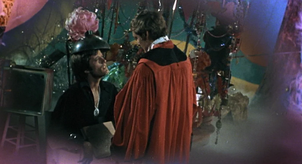 The Trip (1967) movie still: medium — A dark, cluttered room contains hanging decorative beads and metallic abstract structures. One man wears a…