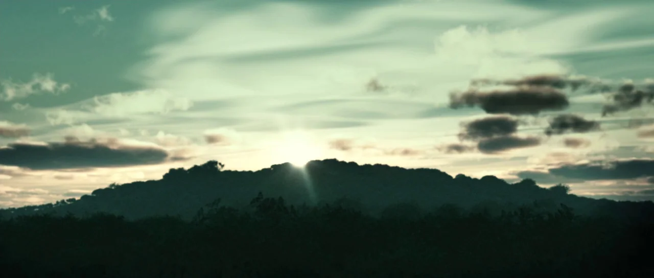 Daybreakers (2009) movie still: establishing — A dark, silhouetted ridge stretches horizontally across the lower third of the frame. The sky above…