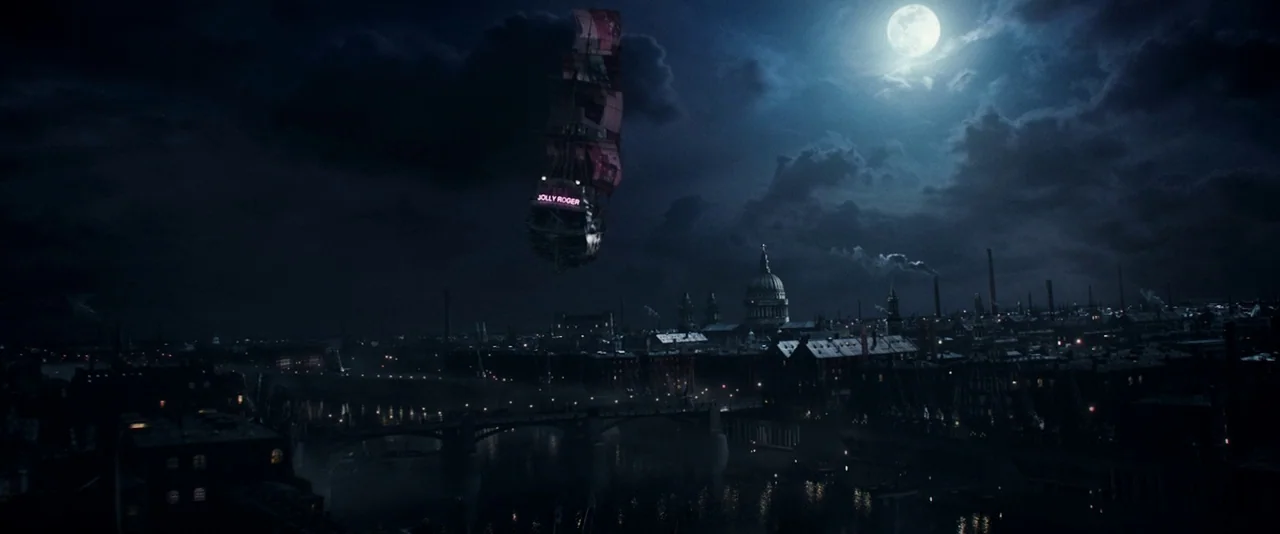 Pan (2015) movie still: establishing — A dark, moody Victorian city skyline at night rests under a large, glowing full moon. An antique wooden…