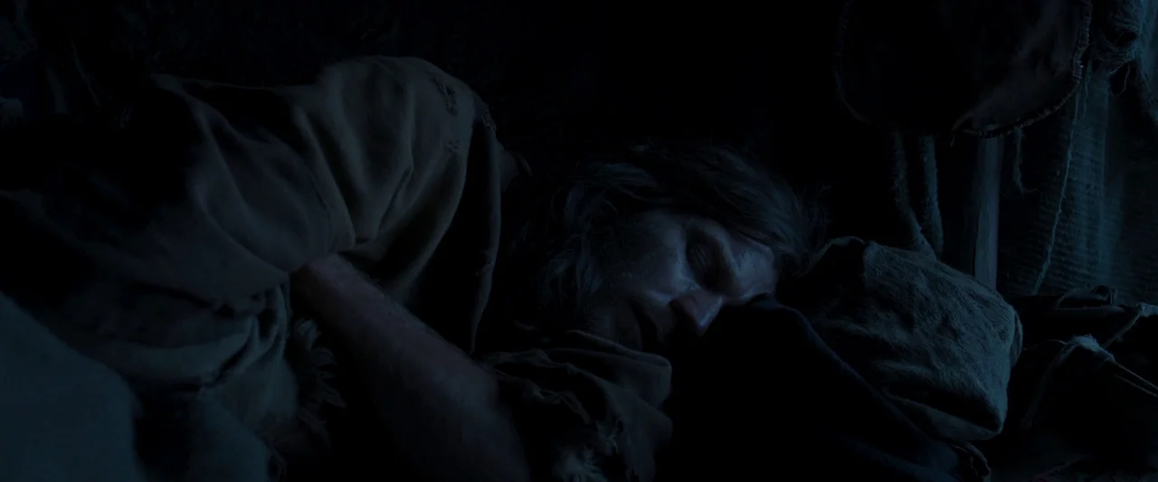 Last Days in the Desert (2015) movie still: closeup — A man lies on a rough bedroll made of thick, dark, textured fabric. The man sleeps with his…