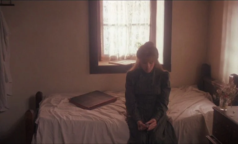 Yentl (1983) movie still: medium — A sparsely furnished 19th-century room features a white-sheeted bed and a window with lace curtains. A young…
