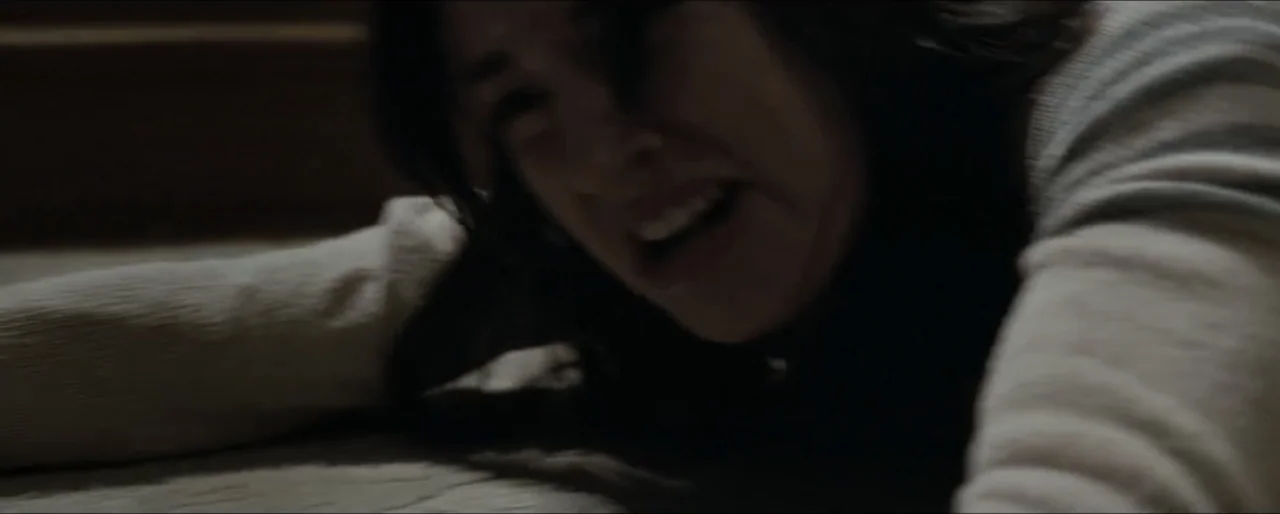 Law Abiding Citizen (2009) movie still: closeup — A dimly lit indoor space featuring a person lying on a soft mattress surface. A woman rests her…