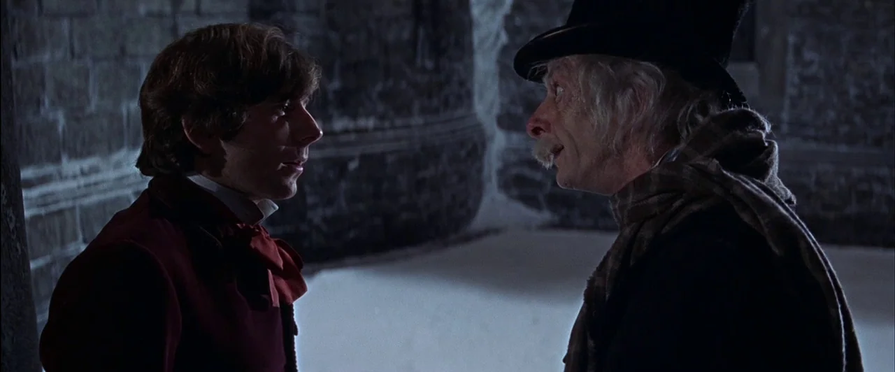 The Fearless Vampire Killers (1967) movie still: medium — Two men stand face-to-face in a dim, dark-stoned interior passage at night. One younger…
