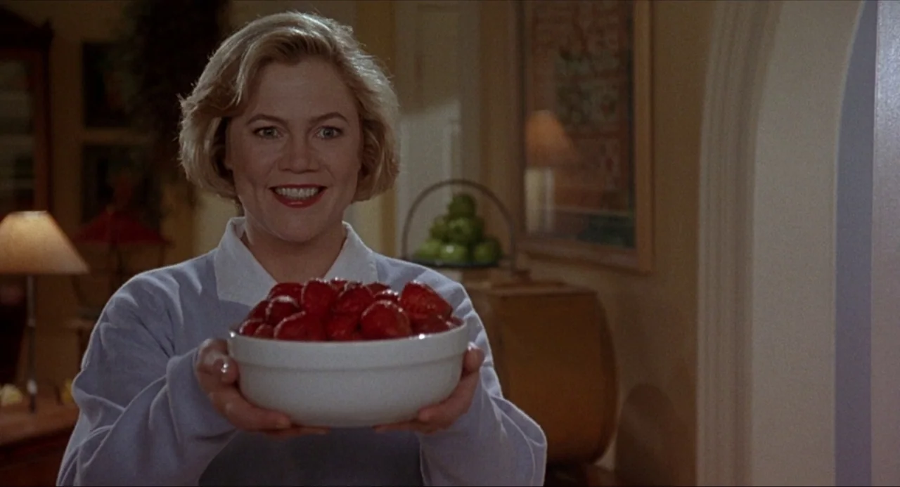 Serial Mom (1994) movie still: medium — A residential interior features a softly lit space with home decor and furniture. A middle-aged woman…