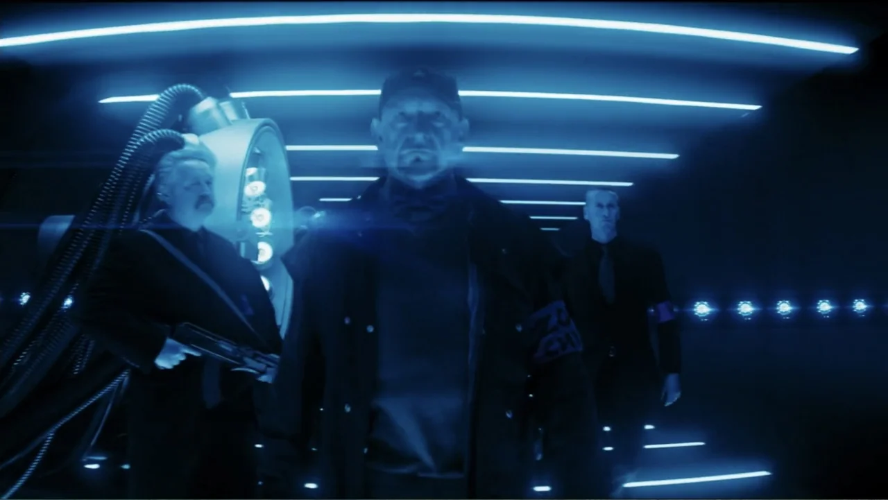 Robot Overlords (2015) movie still: medium — A dark tech corridor features horizontal glowing blue light strips on ceiling and walls. Three men in…