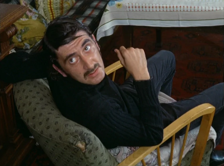 The Merchant Of The Four Seasons (1971) movie still: medium — A furnished interior space features patterned armchairs and a table with a floral…