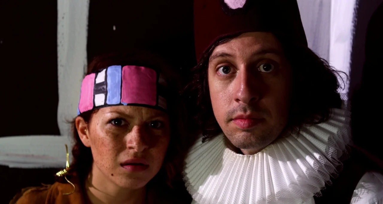 Adam Green’s Aladdin (2016) movie still: closeup — A dark environment features two people positioned closely against a black painted background. A…