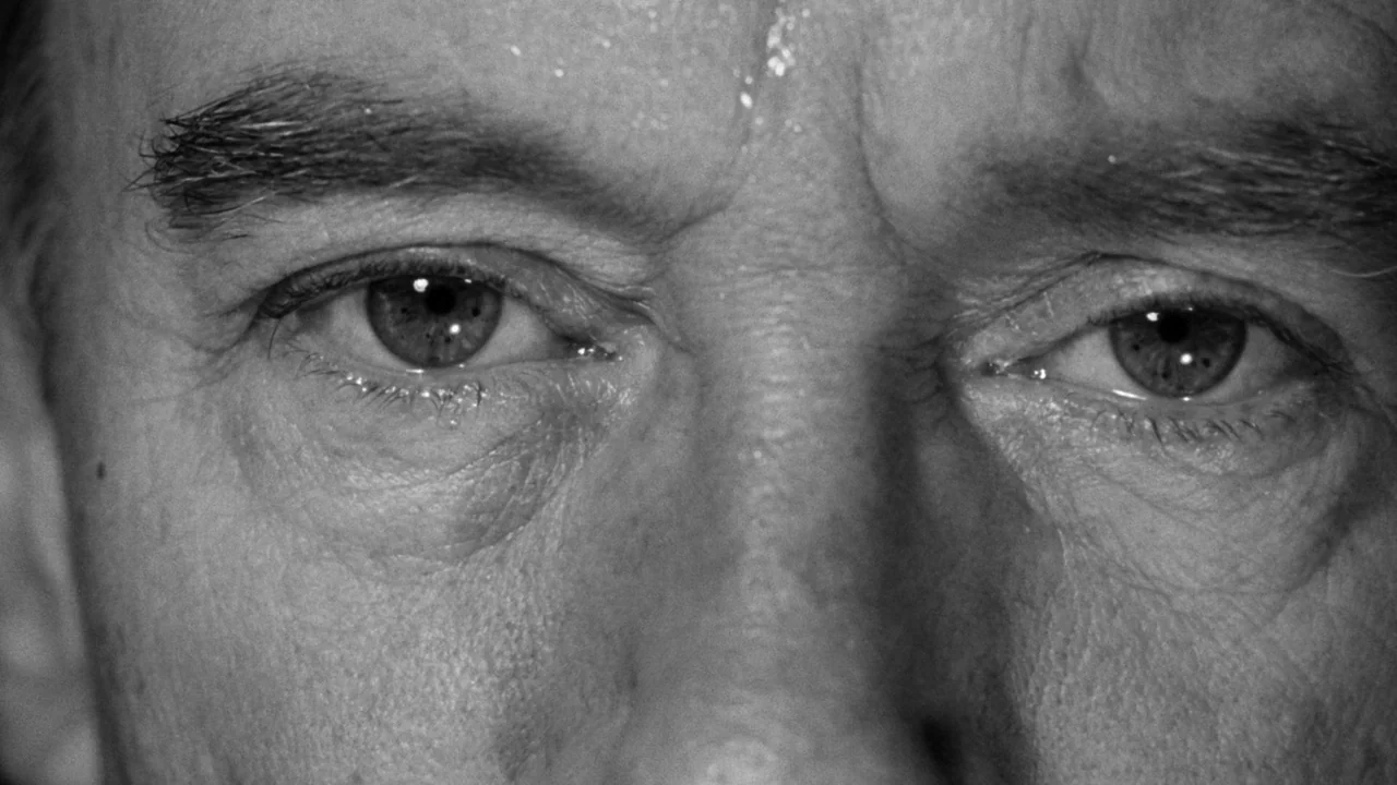 Village of the Damned (1960) movie still: closeup — The frame shows a tightly cropped closeup of an older man's eyes and brow. The skin displays…