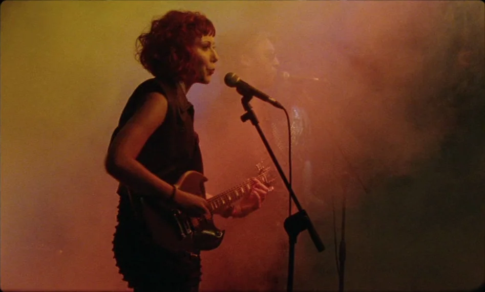 Misunderstood (2014) movie still: medium — A dark concert hall filled with thick haze and warm stage lighting. A red-haired female musician plays an…
