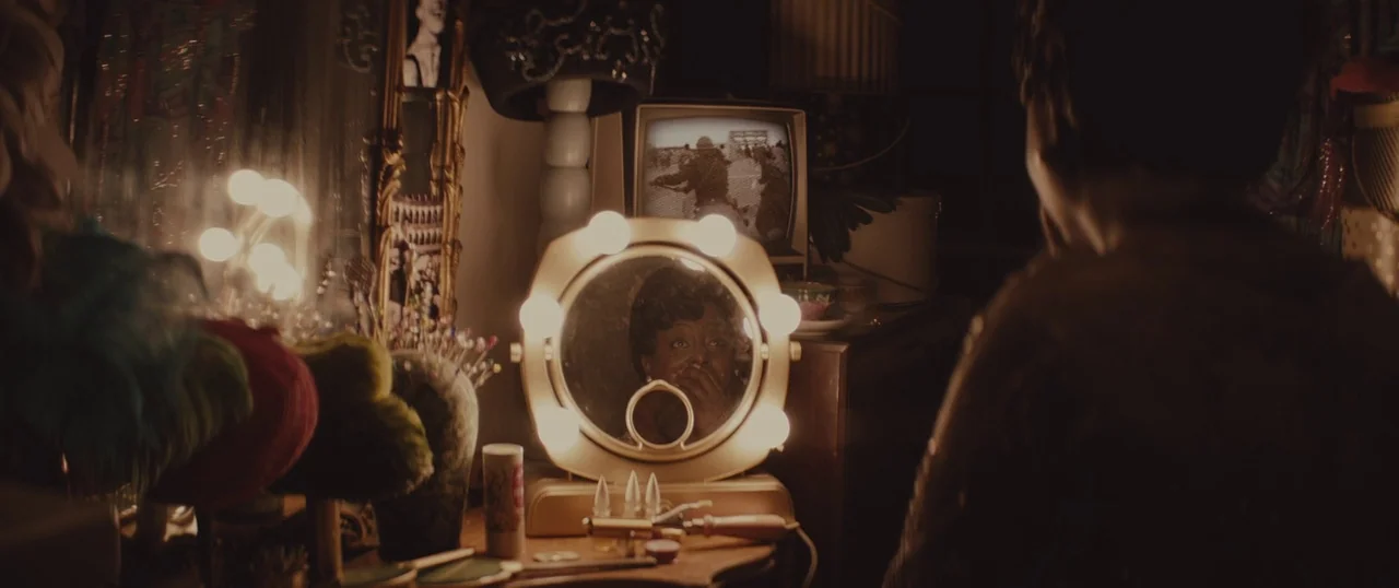 Selma (2014) movie still: medium — A cluttered 1960s vanity table holds a glowing circular mirror and a small television. An elderly woman sits in…