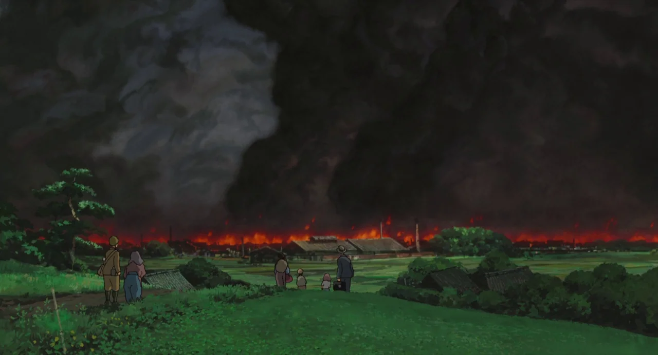 The Wind Rises (2013) movie still: wide — A group of people stand on a grassy hill overlooking a burning rural town. Dark clouds of smoke billow…