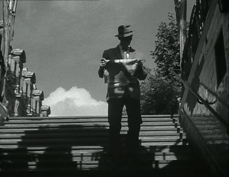 À Bout De Souffle (Breathless) (1960) movie still: fullbody — A man in a fedora and suit descends a stone outdoor staircase. He holds an open…