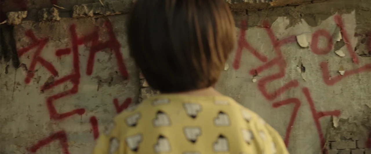 Along with the Gods: The Last 49 Days (2018) movie still: medium — An interior space features crumbling walls covered in bold red spray-painted…