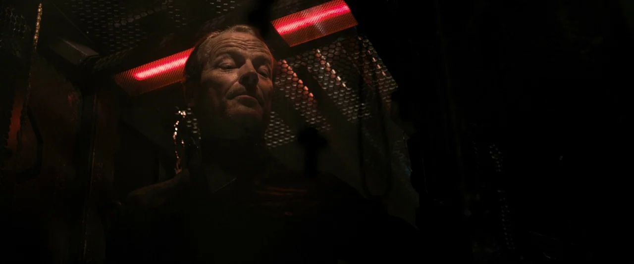 Resident Evil: The Final Chapter (2016) movie still: medium — A dark, cramped industrial interior with metal grating and panels overhead. A man…