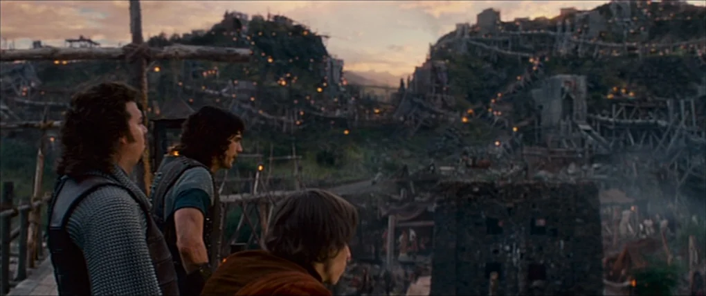Your Highness (2011) movie still: medium — Three men stand on a raised wooden platform overlooking a large, ramshackle hill settlement. The wooden…
