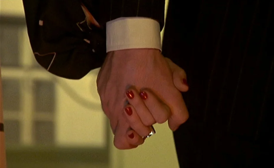The Last Metro (1980) movie still: closeup — A close-up captures two hands intertwined in a well-lit indoor environment. The subjects wear dark…