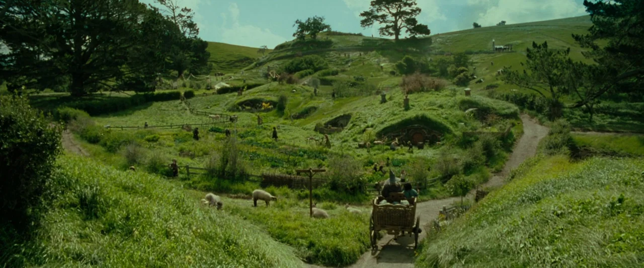The Lord of the Rings: The Fellowship of the Ring (2001) movie still: establishing — A vast green rural landscape features rolling hills, dirt…