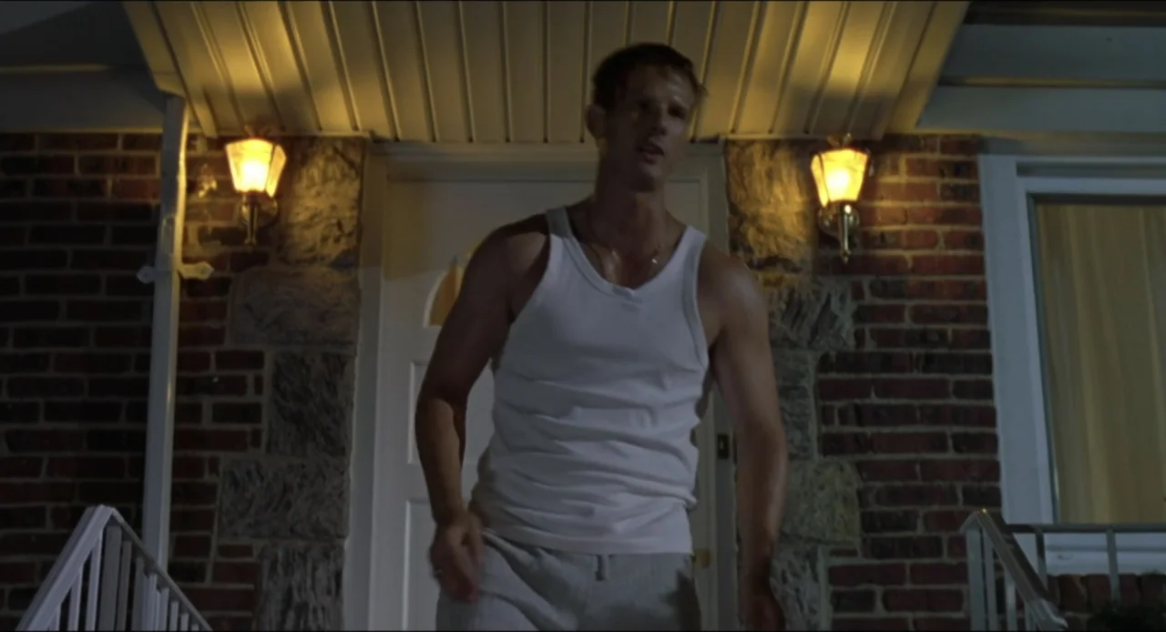 Cop Land (1997) movie still: medium — A man stands on a residential porch at night before a white front door. The exterior wall is constructed of…