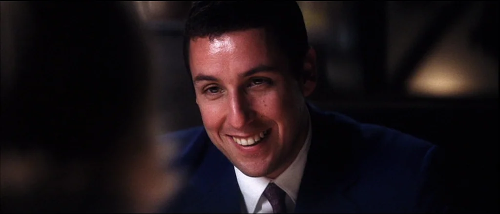 Punch Drunk Love (2002) movie still: closeup — An interior space with dim, dark surroundings characteristic of a late-night diner booth. A man in a…