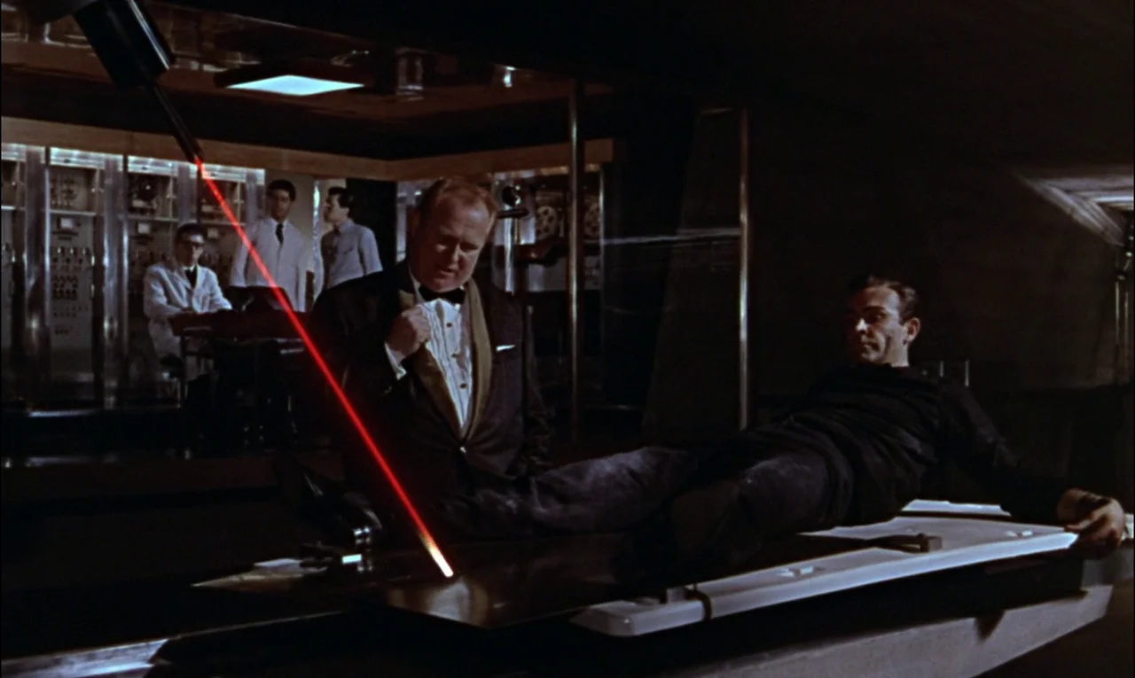Goldfinger (1964) movie still: medium — A dimly lit scientific installation features metallic server banks and computer consoles in the background.…