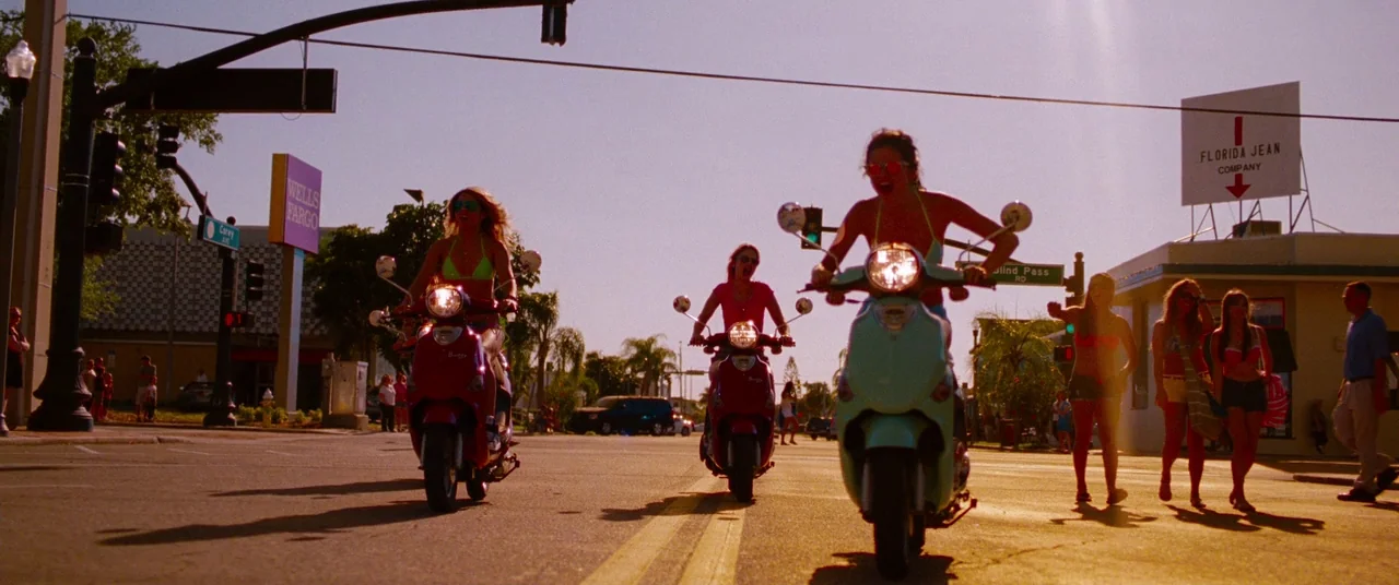 Spring Breakers (2012) movie still: wide — A sunny intersection features various signs including a Wells Fargo bank and Florida Jean Company.…