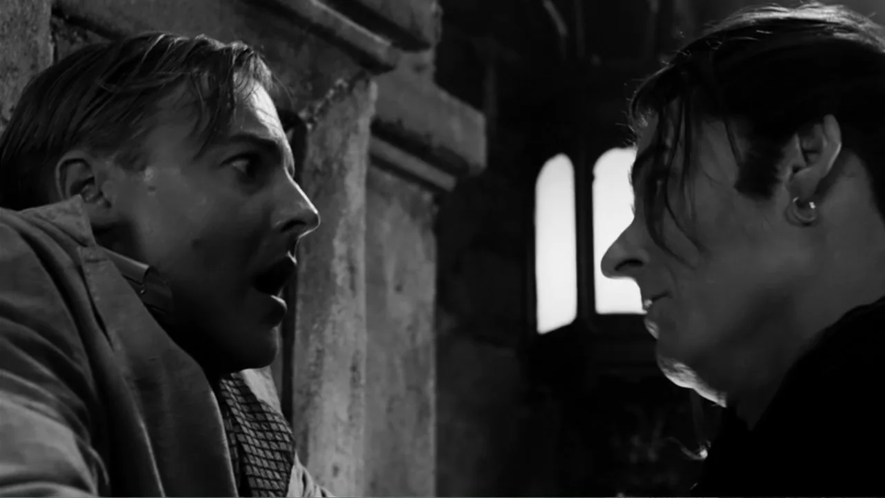 Van Helsing (2004) movie still: medium — A dark stone courtyard lit by a single bright light source near a wall. Two men stand facing each other…