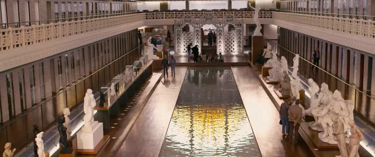 Blue Is The Warmest Colour (2013) movie still: establishing — A spacious gallery features rows of white statues flanking a long rectangular water…