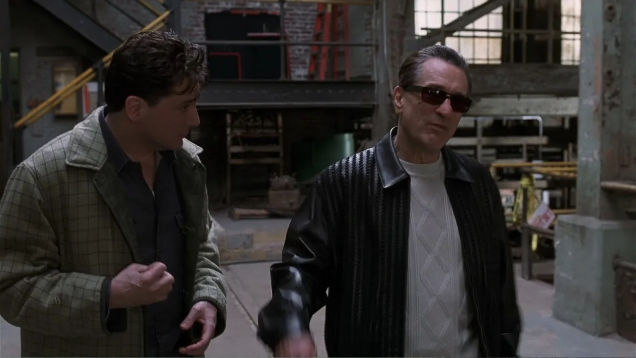 Analyze That (2002) movie still: medium — An industrial building with exposed brick walls, steel beams, and concrete flooring. Two men stand in the…