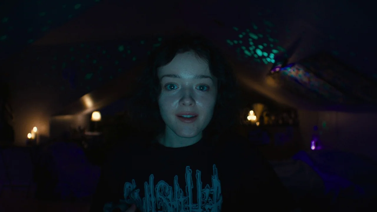We’re All Going to the World’s Fair (2021) movie still: closeup — A dark bedroom at night with glowing projected star patterns on the ceiling. A…