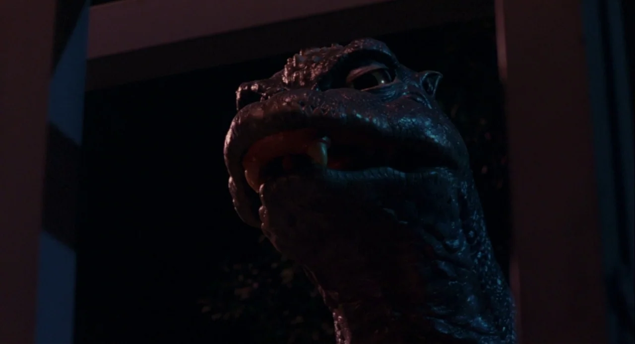 Godzilla vs. Mechagodzilla II (1993) movie still: closeup — A dark night exterior features the close-up head of a reptilian creature. The creature…
