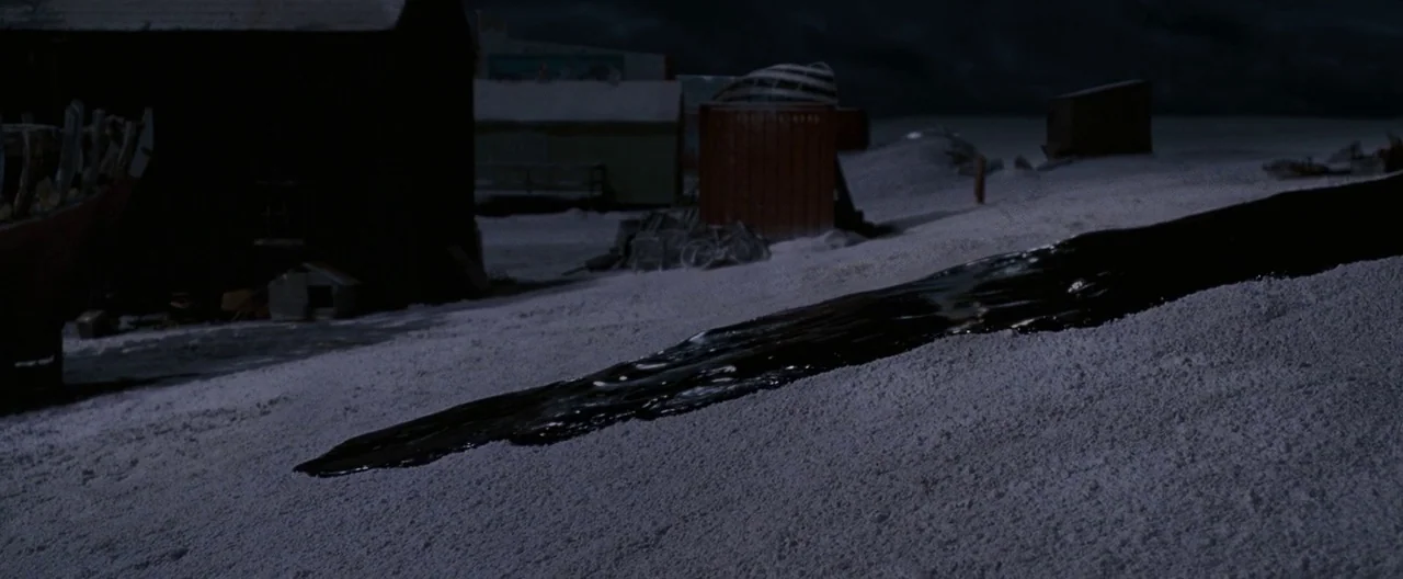 30 Days of Night (2007) movie still: wide — A dark, viscous liquid forms a long trail across a cold, snow-covered environment. Several industrial…