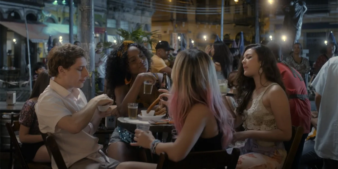An Unforgettable Year - Summer (2023) movie still: medium — Four young adults sit together at a small table at an outdoor city cafe. They are…
